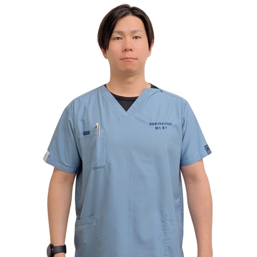 立った姿勢で肩を伸ばし、腕を横に自然に下ろしている男性。ストレッチの開始姿勢。